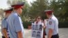 Азаматтық белсенді Әсел Нұрғазиева 2011 жылы желтоқсанда Жаңаөзен оқиғасы кезінде қаза тапқандардың суреттерін ұстап қала әкімдігінің алдында тұр. Жаңаөзен, 29 тамыз 2012 жыл. (Көрнекі сурет)