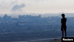 Raseljeni palestinski dječak posmatra dim koji se diže iznad grada Gaze tokom izraelske vojne operacije, 1. oktobra 2025.