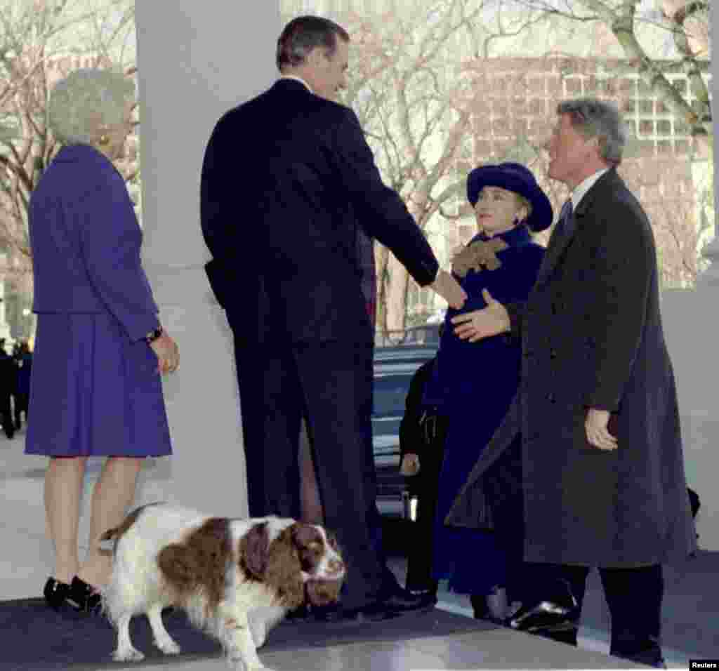 20 января 1993 года. Избранный президент Билл Клинтон (справа) вместе с женой Хиллари Клинтон здоровается с 41-м президентом Джорджем Бушем (слева) и первой леди Барбарой Буш во время визита в Белый дом. Позади Бушей, на переднем плане – их пес Милли